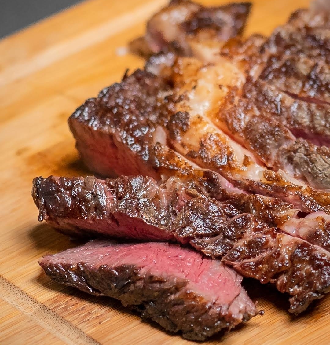 Corte de carne selada e fatiada sobre tábua de madeira